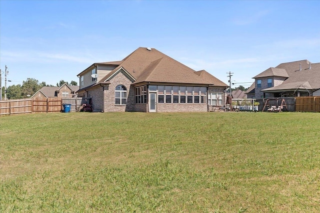 back of property featuring a sunroom and a lawn