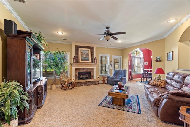 carpeted living room featuring ceiling fan, a fireplace, and crown molding