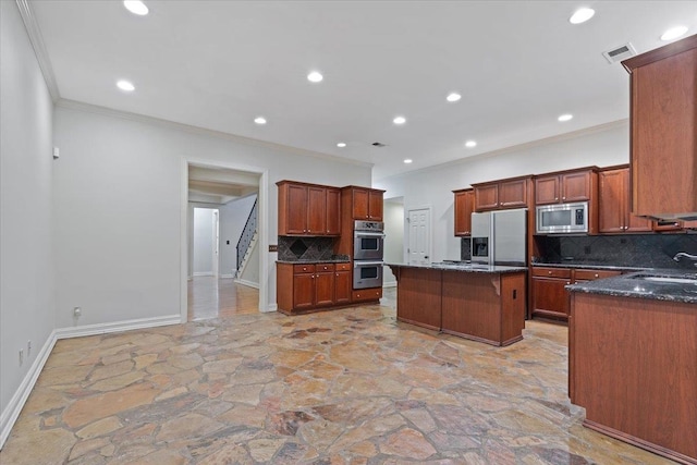 kitchen with dark stone counters, tasteful backsplash, a kitchen island, appliances with stainless steel finishes, and crown molding