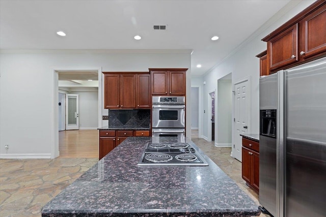 kitchen with decorative backsplash, dark stone countertops, ornamental molding, and stainless steel appliances