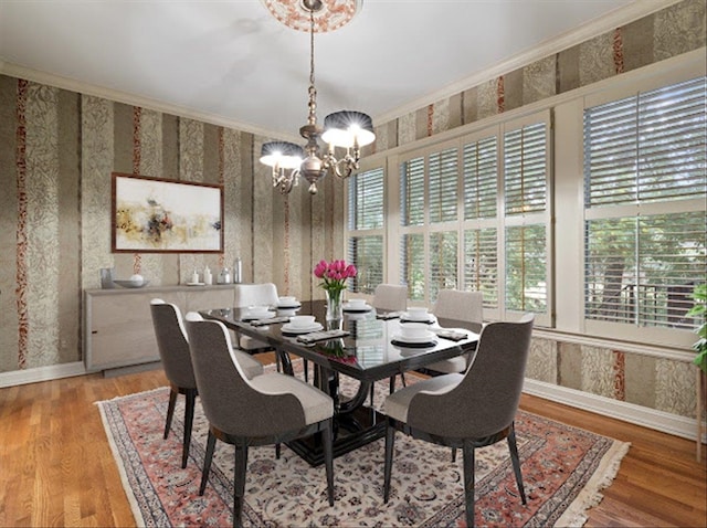 dining area featuring an inviting chandelier, wood-type flooring, a healthy amount of sunlight, and crown molding