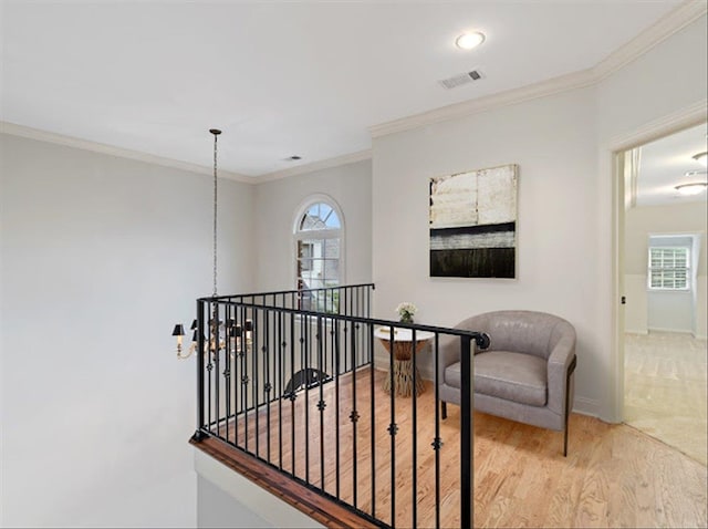 hall with a chandelier, light hardwood / wood-style floors, and crown molding