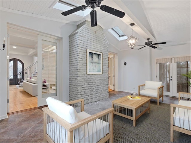 living room with ceiling fan with notable chandelier, lofted ceiling with skylight, and hardwood / wood-style flooring