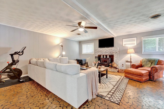 living room with ceiling fan, plenty of natural light, a fireplace, and a textured ceiling