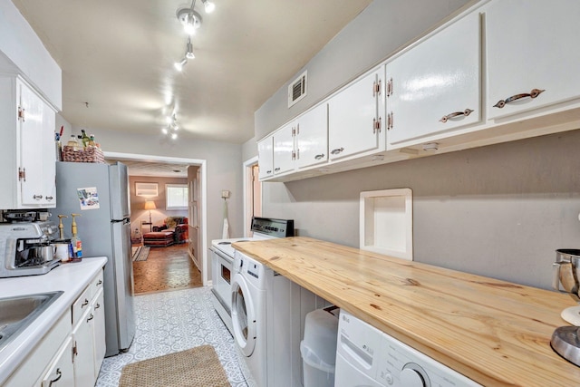 kitchen featuring rail lighting, washer / dryer, and white cabinetry