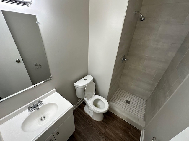 bathroom with vanity, hardwood / wood-style flooring, toilet, and tiled shower