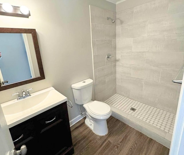 bathroom with tiled shower, hardwood / wood-style floors, vanity, and toilet