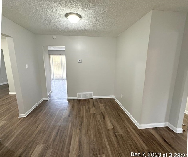 unfurnished room with a textured ceiling and dark hardwood / wood-style floors