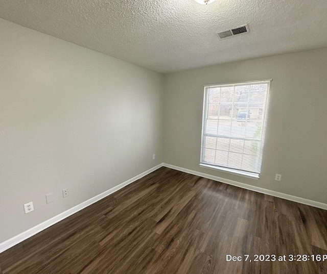 empty room featuring a textured ceiling and dark wood-type flooring