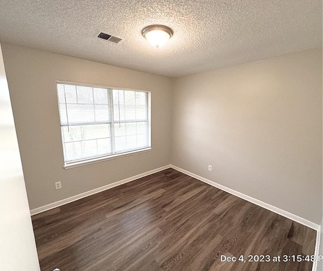 spare room featuring a textured ceiling and dark hardwood / wood-style flooring