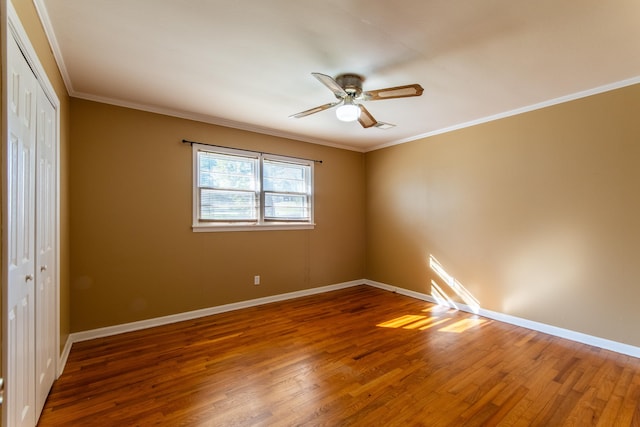 unfurnished bedroom featuring wood-type flooring, crown molding, ceiling fan, and a closet