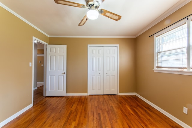 unfurnished bedroom featuring wood-type flooring, a closet, ornamental molding, and ceiling fan