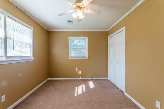 unfurnished bedroom featuring ceiling fan, a closet, light carpet, and ornamental molding