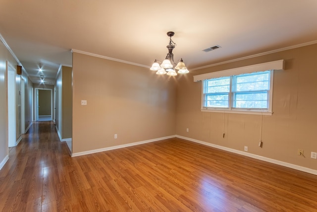 empty room featuring a notable chandelier, hardwood / wood-style floors, and crown molding