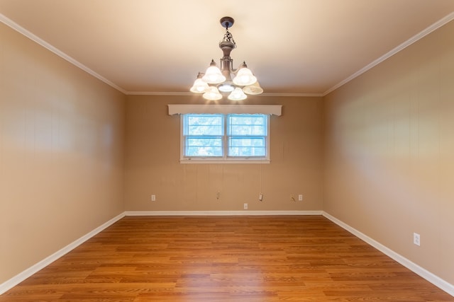 empty room featuring a chandelier, light hardwood / wood-style floors, and crown molding