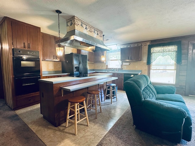 kitchen with pendant lighting, a wealth of natural light, a center island, and black appliances