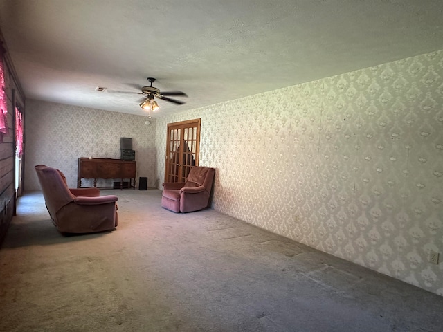 sitting room with ceiling fan, carpet floors, and a textured ceiling