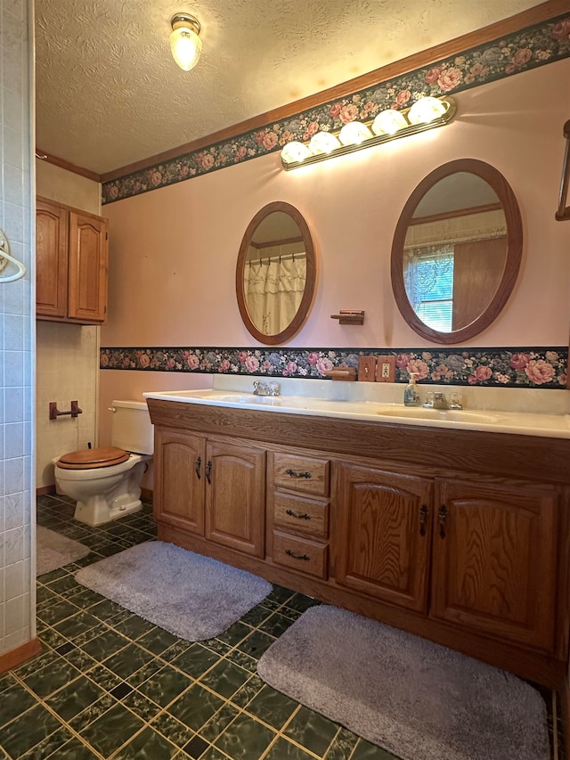 bathroom with a textured ceiling, vanity, and toilet