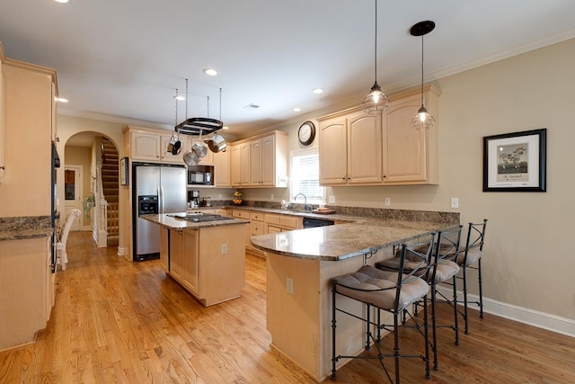 kitchen with kitchen peninsula, appliances with stainless steel finishes, a kitchen breakfast bar, dark stone counters, and light hardwood / wood-style floors