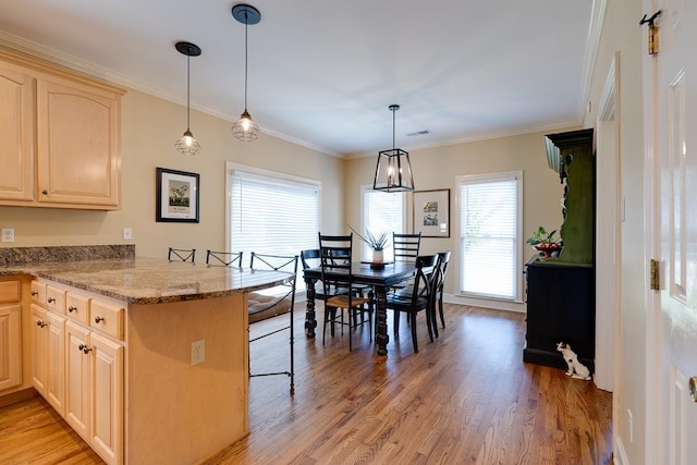 kitchen featuring kitchen peninsula, crown molding, hardwood / wood-style floors, and hanging light fixtures