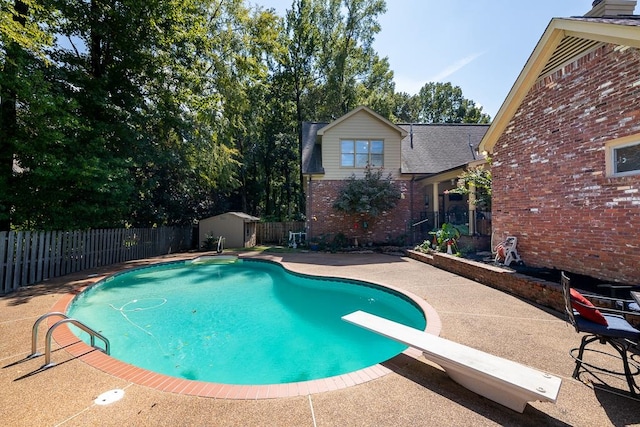 view of pool featuring a patio, a shed, and a diving board