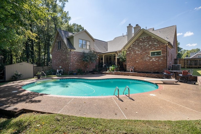 view of pool featuring a storage unit, a diving board, and a patio