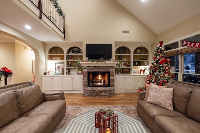 living room with a brick fireplace, light wood-type flooring, and high vaulted ceiling