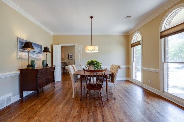 dining area featuring hardwood / wood-style floors, a wealth of natural light, and crown molding