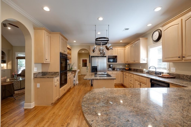 kitchen with light wood-type flooring, ornamental molding, sink, black appliances, and a center island