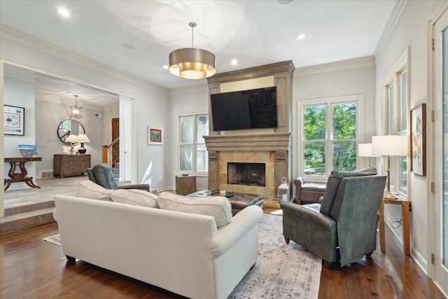 living room featuring ornamental molding, a tiled fireplace, a chandelier, and dark hardwood / wood-style flooring