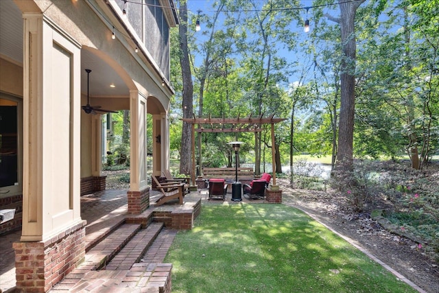 view of yard featuring a pergola, ceiling fan, a patio area, and an outdoor living space with a fire pit