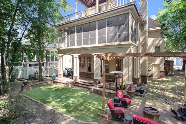 back of house featuring a sunroom, a balcony, a patio area, and a lawn