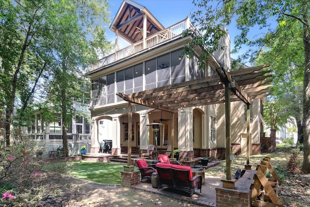 back of property with a balcony, an outdoor living space with a fire pit, a pergola, and a patio