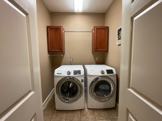 laundry area with washer and clothes dryer, light tile patterned floors, and cabinets