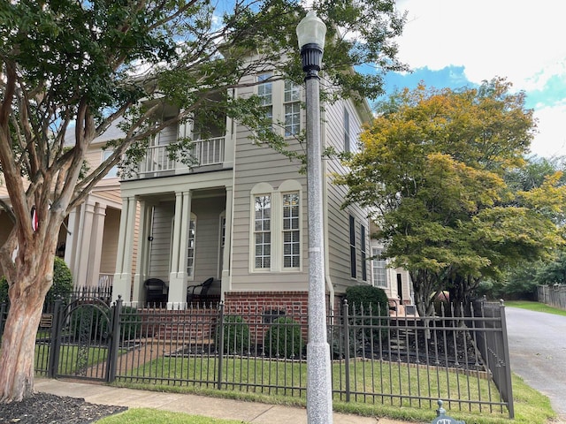 view of front of property featuring a balcony, a front lawn, and covered porch