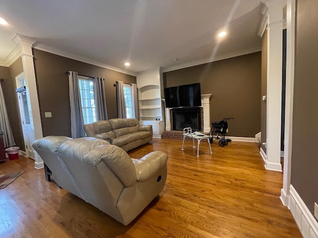 living room with a brick fireplace, light wood-type flooring, and crown molding