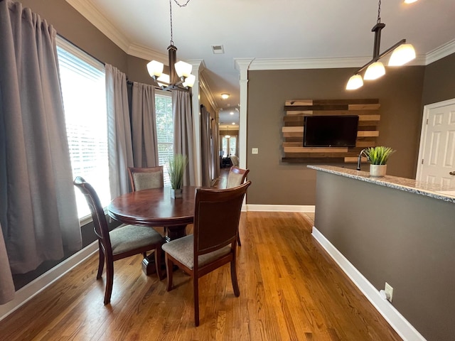 dining room with ornamental molding, wood-type flooring, and a notable chandelier