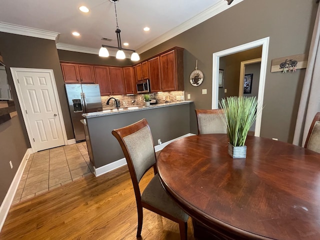 dining room featuring light wood-type flooring, sink, and crown molding