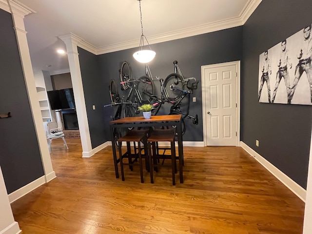 dining room with decorative columns, ornamental molding, and hardwood / wood-style floors