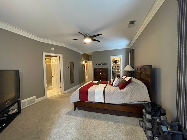 bedroom featuring a closet, ceiling fan, a walk in closet, ornamental molding, and light carpet