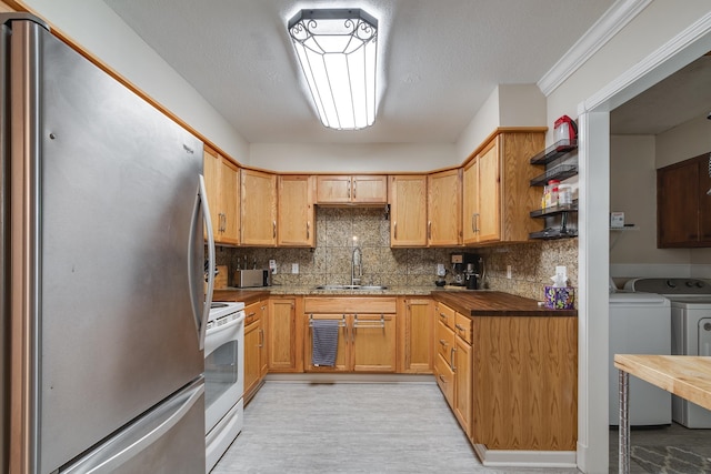 kitchen with stainless steel refrigerator, crown molding, white electric range, washer and clothes dryer, and sink