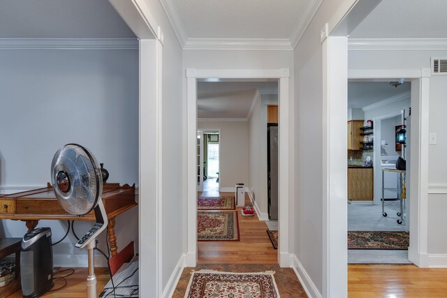 hallway with hardwood / wood-style flooring and ornamental molding