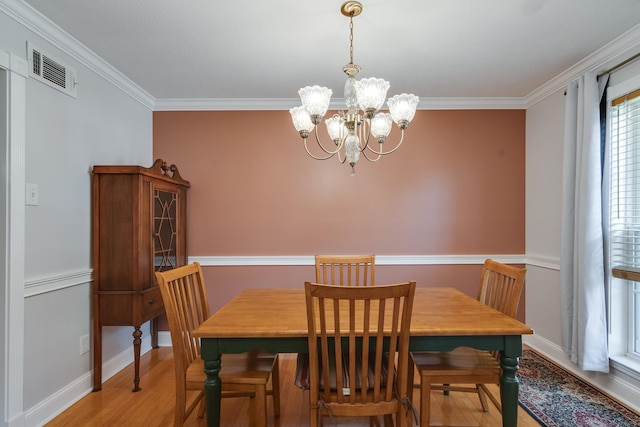 dining space featuring a notable chandelier, light wood-type flooring, and crown molding