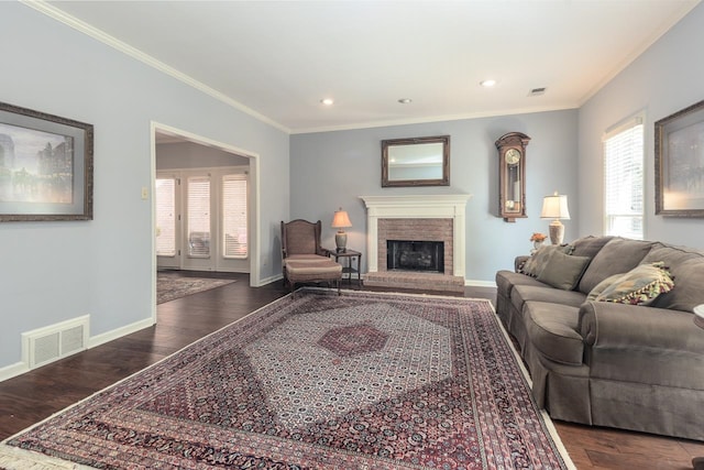 living room with a brick fireplace, crown molding, and dark hardwood / wood-style flooring