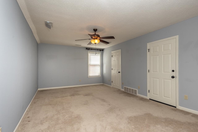 unfurnished room with ceiling fan, light colored carpet, and a textured ceiling