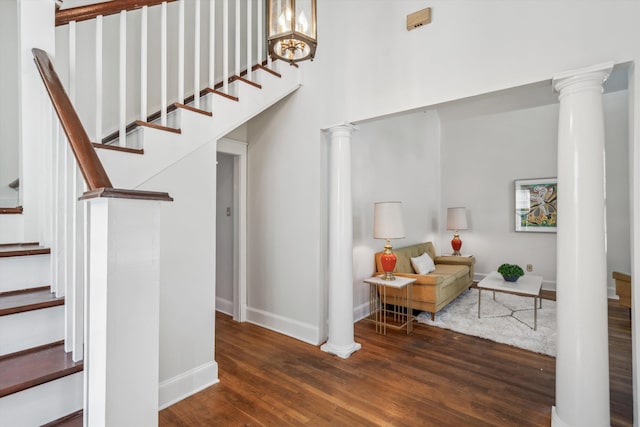 stairway with a notable chandelier, hardwood / wood-style floors, and ornate columns