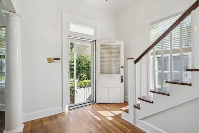 foyer featuring wood-type flooring and decorative columns