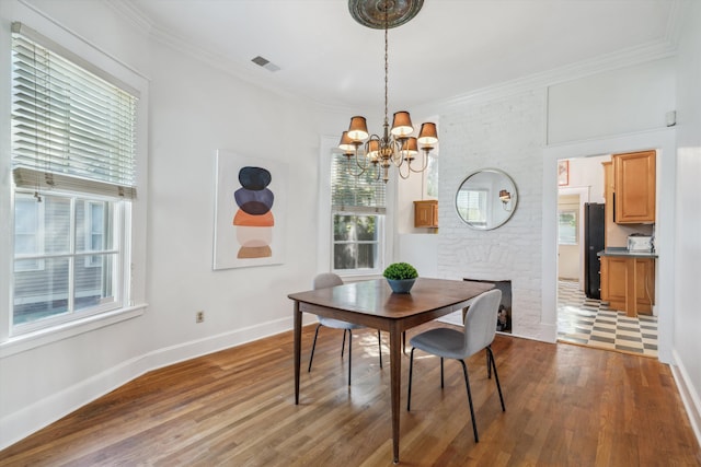 dining room with a notable chandelier, dark wood-type flooring, a fireplace, and crown molding