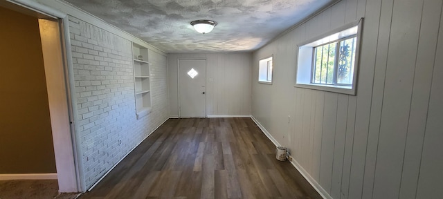 doorway featuring a textured ceiling, dark hardwood / wood-style floors, crown molding, and built in features