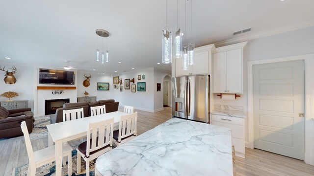 dining space with ceiling fan with notable chandelier and light hardwood / wood-style flooring